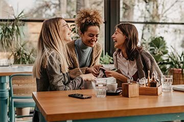 Three friends having their coffee togther while smiling. 
