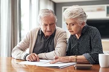 Senior couple sitting at a table going over documents.