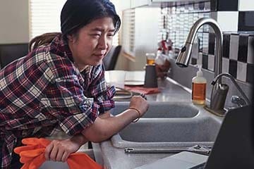 woman repairing sink in kitchen