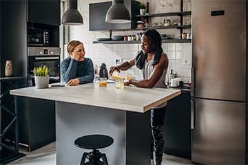 Image of a couple drinking orange juice at their kitchen counter