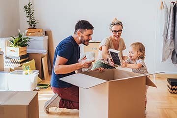A family with a child unpacking boxes in a new home. 