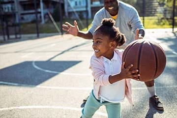Close up of a father taking his daughter to play some basketball in the park