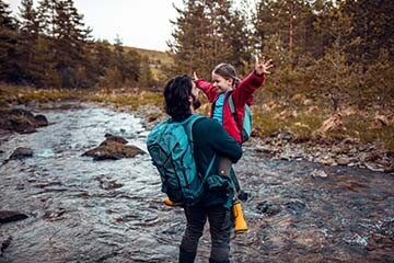 Father holding daughter while crossing a stream