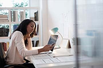 Woman sitting at home desk looking at her phone
