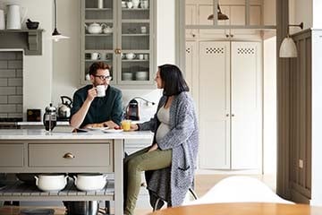 A man and woman are having a conversation while eating breakfast in their kitchen.