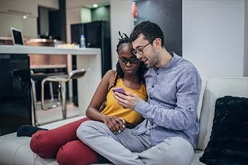 Couple looking at a phone while sitting on their sofa