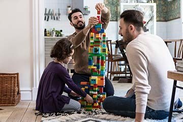 Family of three plays with building blocks on the floor