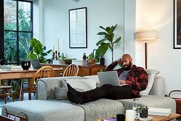  Image of a man on his computer while lounging on the couch