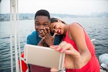 Couple takes engagement selfie on a sailboat.