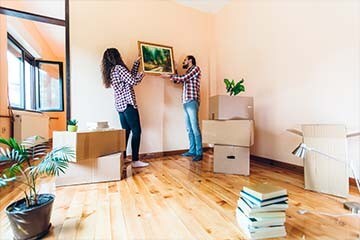 Man and woman hang picture as unpacking in new home