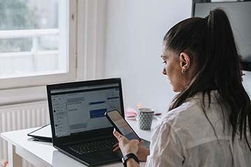 Woman working from home and looking at her phone