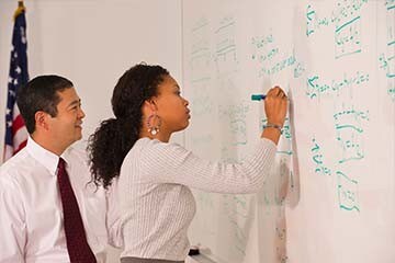 Image of a woman working through a formula on a whiteboard