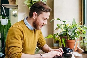 Man Sitting In Café Using Laptop