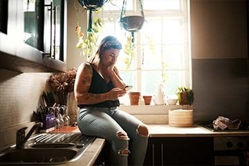 Woman sitting on counter looking at her phone