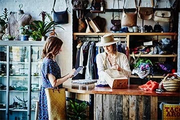 Woman paying for her recent retail purchase at a leather goods store with her digital wallet.
