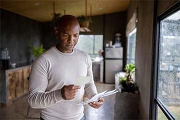 Man at home reading a letter in the mail and looking worried