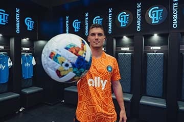 Kristijan Kahlina stands in the Charlotte FC locker room holding a soccer ball in front of the camera