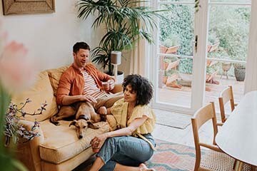 oung couple relaxing in their living room on their yellow couch with their new dog