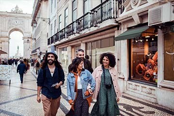 A group of friends happily walks down a city street while on vacation