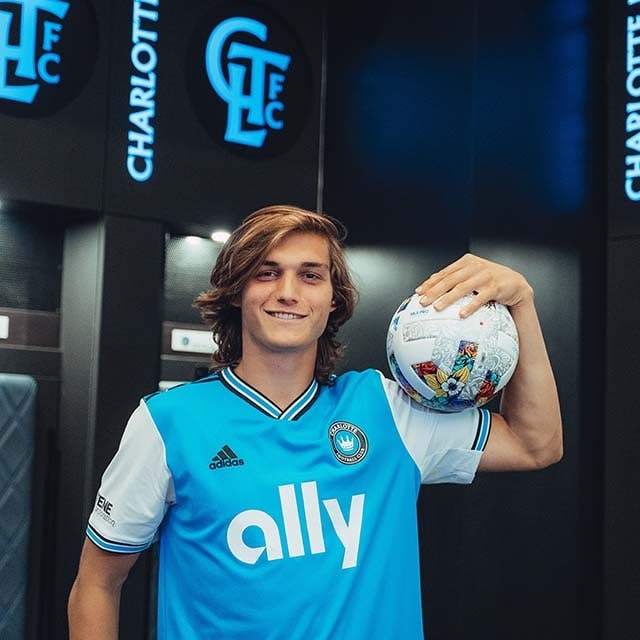 Image of Charlotte FC player Ben Bender holding a soccer ball and smiling at the camera.