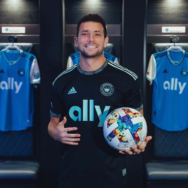 Brandt Bronico poses in front of Charlotte FC jerseys in a locker room