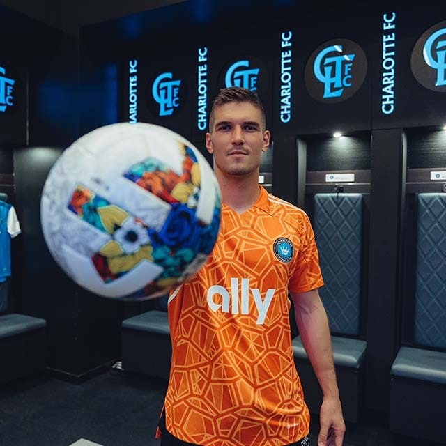 Kristijan Kahlina stands in the Charlotte FC locker room holding a soccer ball in front of the camera