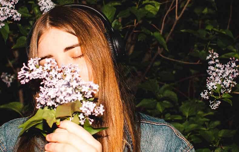 Young woman listening to music and smelling flowers