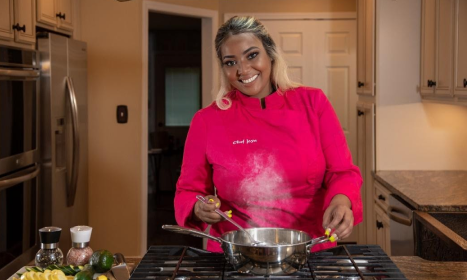 Chef Joya posing in a kitchen with a pot in hand