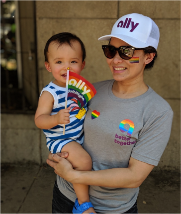 Ally team member holding a baby at a pride event