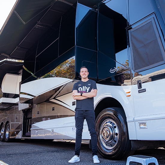 Alex Bowman stands outside of his Prevost tour bus